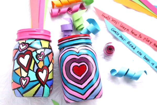 colourful painted mason jars with curled up strips of paper in them. 